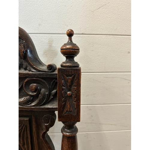 36 - A single oak Jacobean style hall chair with a carved lion back and turned supports finishing in deco... 