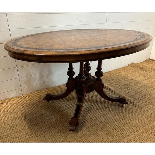 42 - An oval walnut centre table with ebonised inlay and pierced floral detail, on four splayed legs with... 