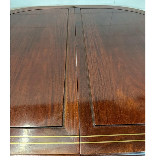 43 - An extendable oval mahogany dining table with brass string inlay on turned legs with an accompanying... 