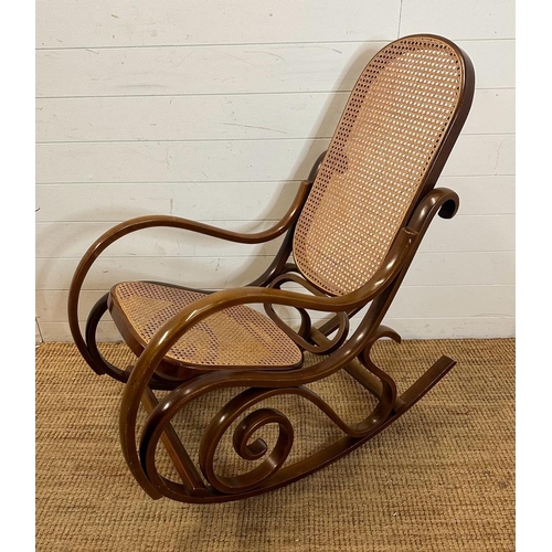 44 - A scrolling Bentwood rocking chair with rattan back and seat