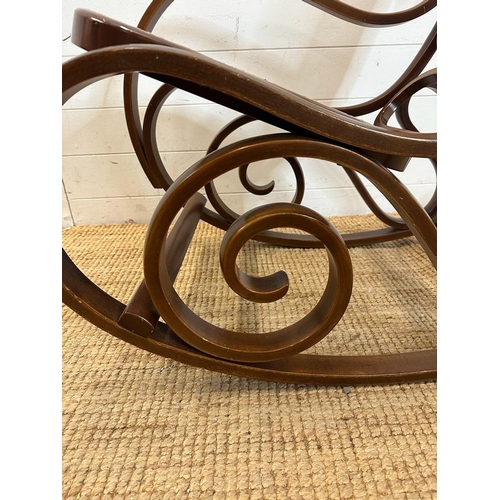 44 - A scrolling Bentwood rocking chair with rattan back and seat