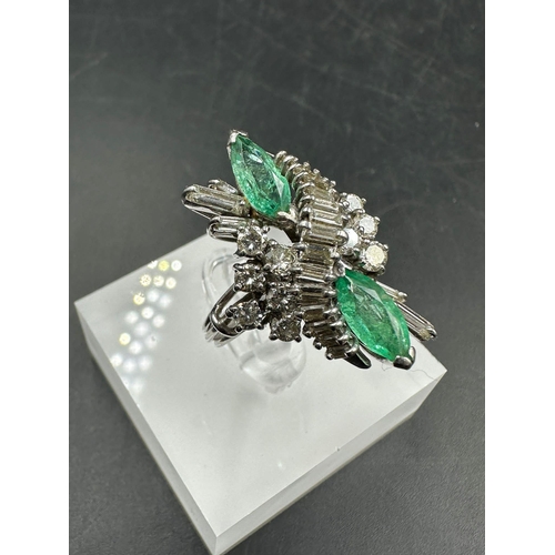 602 - An emerald and diamond ring, designed a s a vertically set elongated cluster with two marquise cut e... 