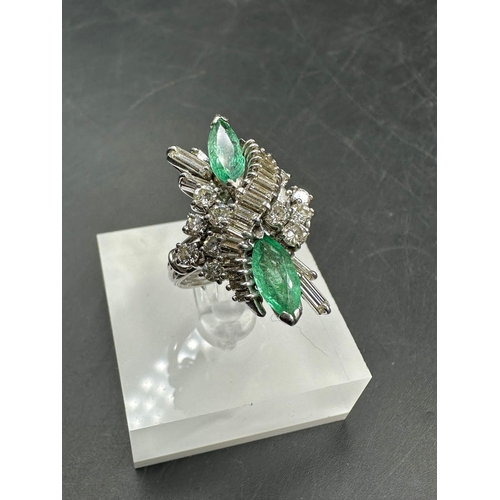 602 - An emerald and diamond ring, designed a s a vertically set elongated cluster with two marquise cut e... 