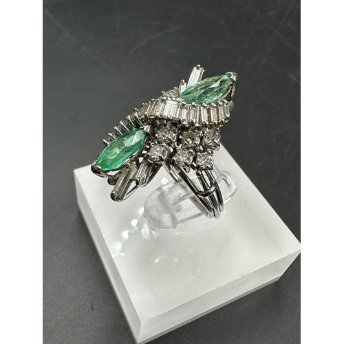 602 - An emerald and diamond ring, designed a s a vertically set elongated cluster with two marquise cut e... 