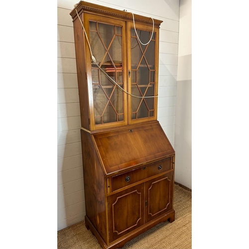 66 - A yew bureau bookcase comprising of a glazed two shelf bookcase and a red leather topped bureau with... 