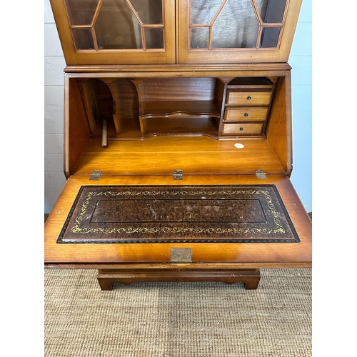 66 - A yew bureau bookcase comprising of a glazed two shelf bookcase and a red leather topped bureau with... 