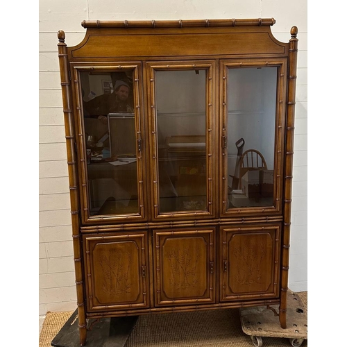 69 - A bamboo effect glazed cabinet with two glass shelves and three embossed cupboards under (H200cm W13... 