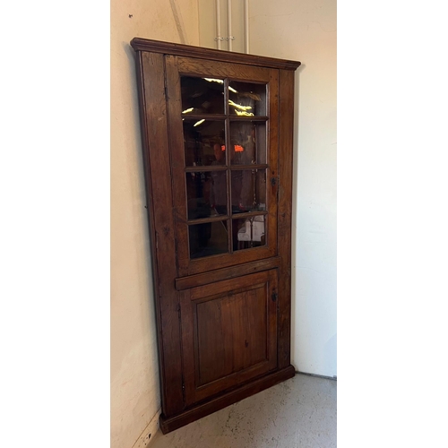 72 - An oak corner cupboard with glazed door and panelled cupboard (H210cm W95cm D64cm)