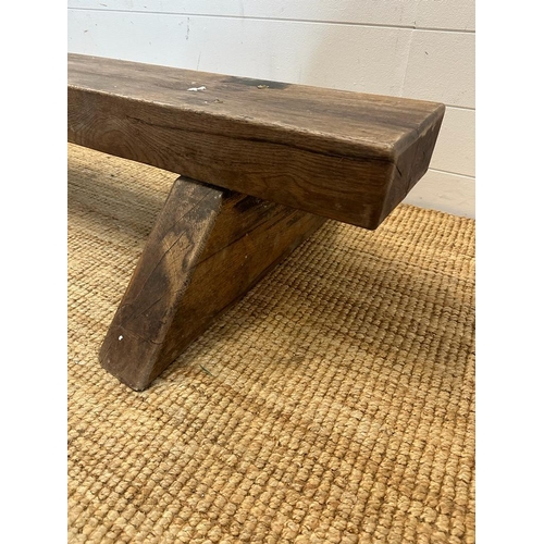 74 - A reclaimed oak bench on triangular feet (H30cm W180cm)