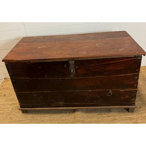 86 - A large wooden chest with wrought iron lock on wooden feet (H70cm W121cm D60cm)