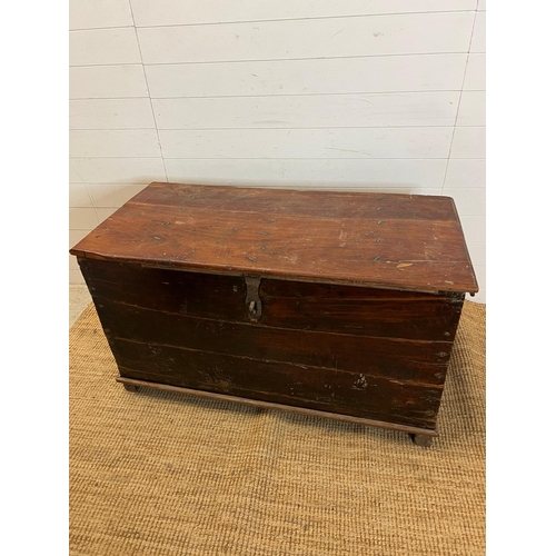 86 - A large wooden chest with wrought iron lock on wooden feet (H70cm W121cm D60cm)