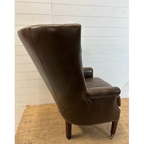 101 - A brown leather button backed wing arm chair by Henredon leather company with brass studs and castor... 