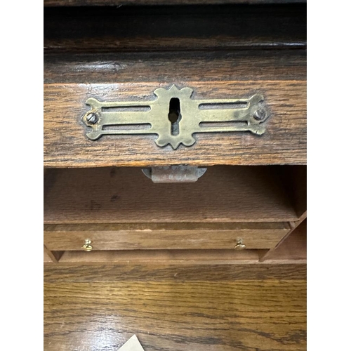 105 - An Edwardian oak roll top desk comprising of six drawers, storage compartments and original key (H11... 