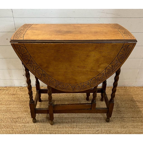 127 - An oak gate leg table with carved top and barley twist legs (H72cm W108cm D74cm extension W37cm down... 