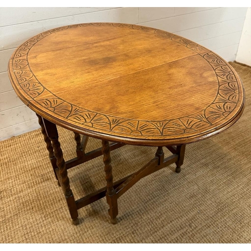 127 - An oak gate leg table with carved top and barley twist legs (H72cm W108cm D74cm extension W37cm down... 