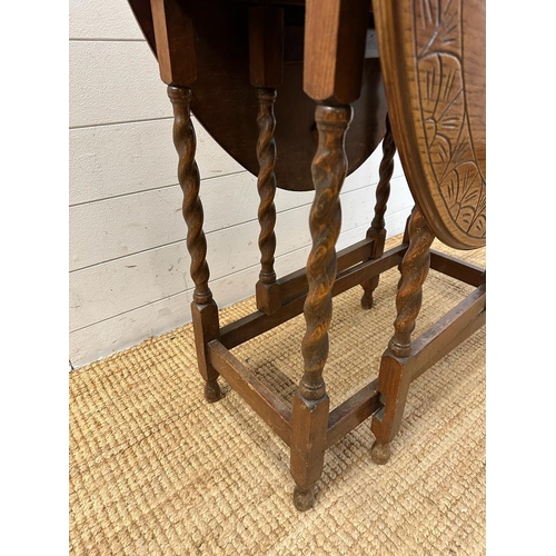 127 - An oak gate leg table with carved top and barley twist legs (H72cm W108cm D74cm extension W37cm down... 