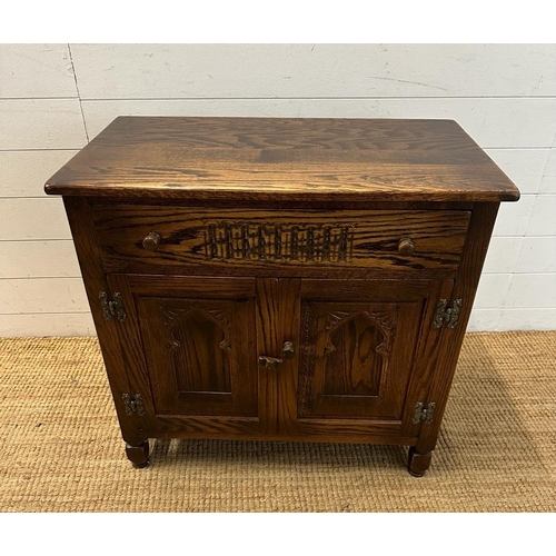 176 - An oak two door cabinet with single drawer over and carved panels (H72cm W76cm D44cm)