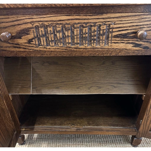 176 - An oak two door cabinet with single drawer over and carved panels (H72cm W76cm D44cm)