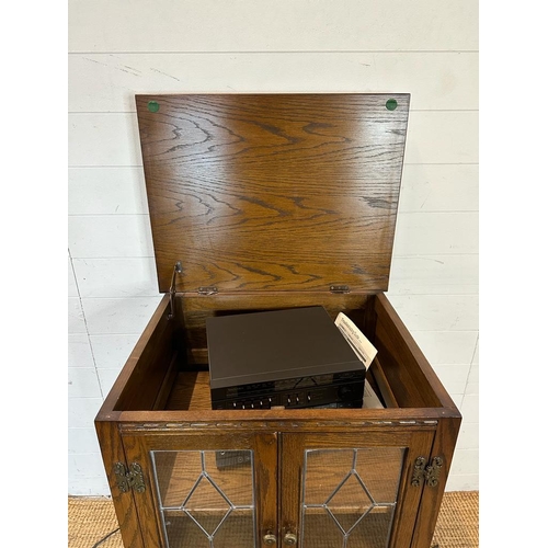 188 - An oak glazed media cabinet with leaded glass and carved detail to doors (H94cm W62cm D49cm)