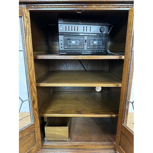 188 - An oak glazed media cabinet with leaded glass and carved detail to doors (H94cm W62cm D49cm)