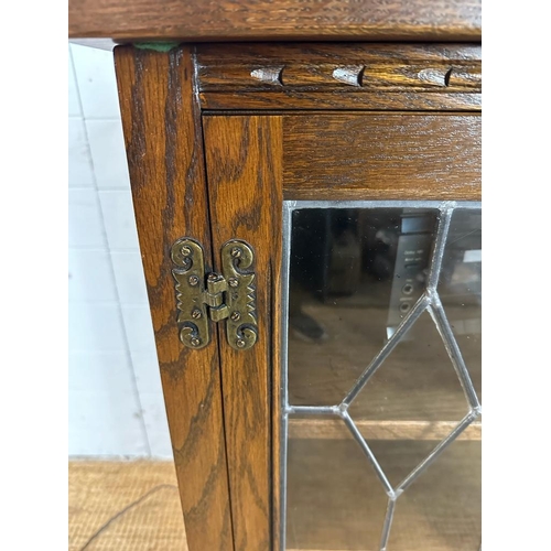 188 - An oak glazed media cabinet with leaded glass and carved detail to doors (H94cm W62cm D49cm)