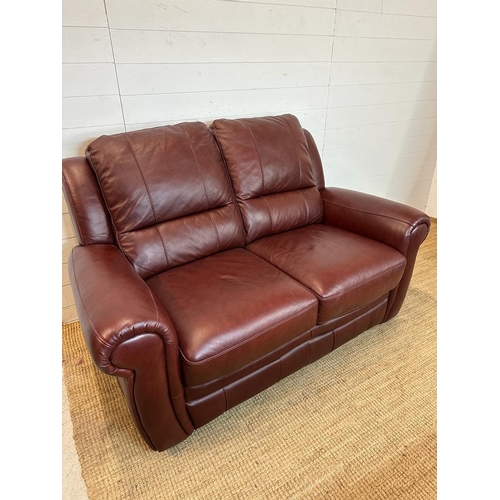 189 - A red leather three piece suite comprising of two arm chairs and a two seater sofa