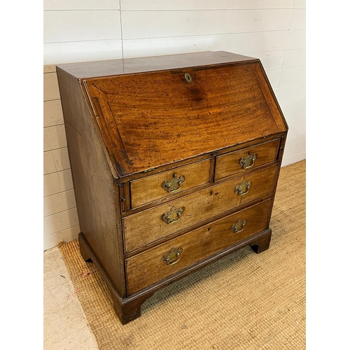 21 - An oak bureau opening to writing slope and bracket feet (H104cm W92cm D56cm)