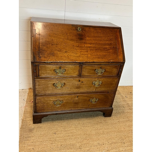 21 - An oak bureau opening to writing slope and bracket feet (H104cm W92cm D56cm)