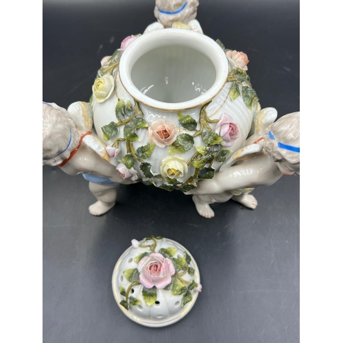 378 - A Sitzendorf porcelain center piece with three cherubs supporting a lidded bowl decorated with flowe... 