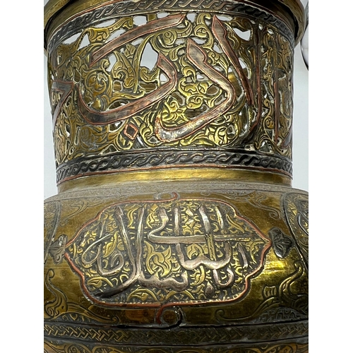 393 - An Islamic vase, the brass vessel is inlaid with copper and Arabic calligraphy (H17cm Dia15cm)