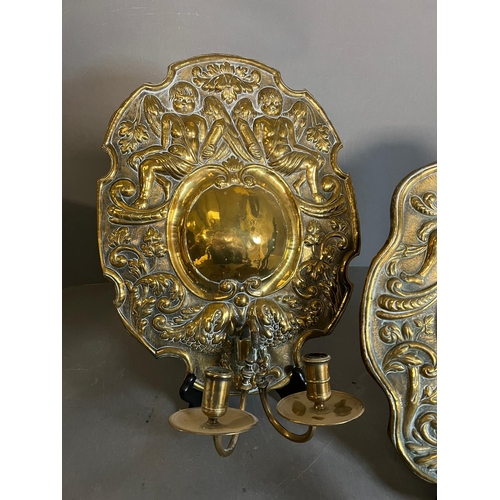 402 - A pair of brass wall sconce, cast backplate with winged cherubs and twin arm candle holders