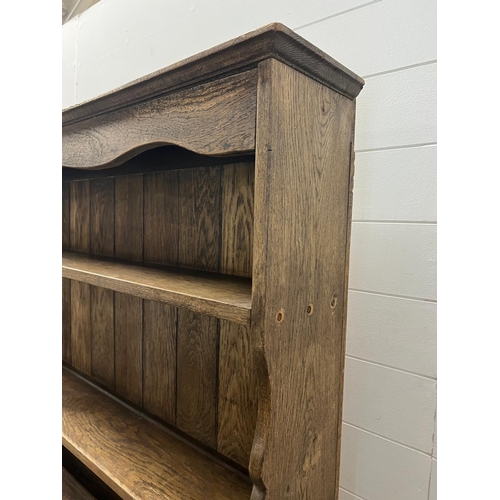 42 - A rustic oak dresser, Plate rack sits on a base comprising of drawers and cupboards (H193cm W138cm D... 