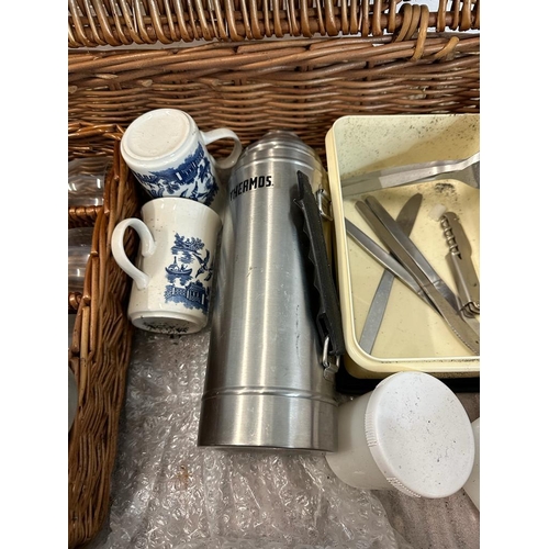 445 - A wicker picnic basket comprising of blue and white plates, cutlery, thermos and plastic glasses