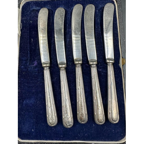 484 - An incomplete set of five silver handled butter knives, cased.