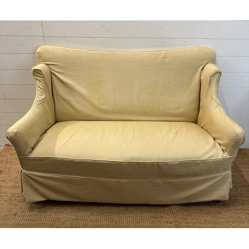 6 - A two seater cream upholstered skirted sofa