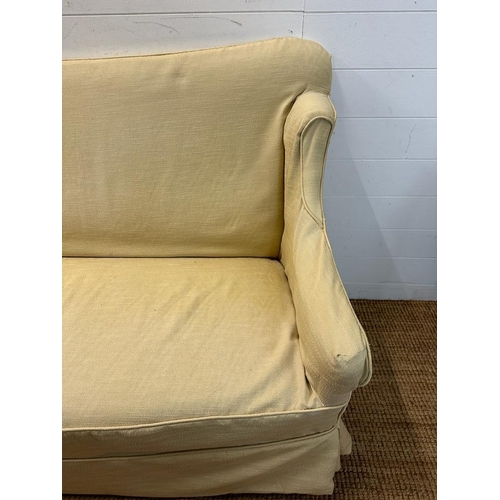 6 - A two seater cream upholstered skirted sofa