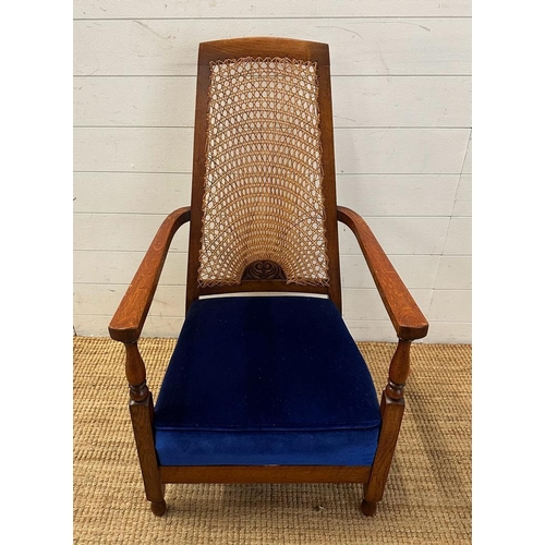 81 - An oak cane backed arts and crafts style arm chair upholstered in blue