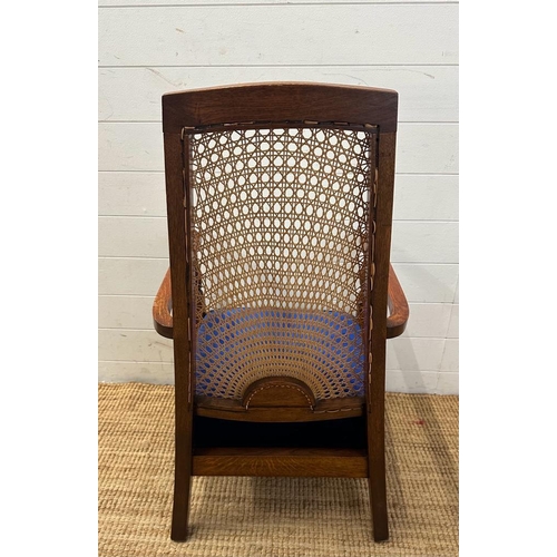 81 - An oak cane backed arts and crafts style arm chair upholstered in blue