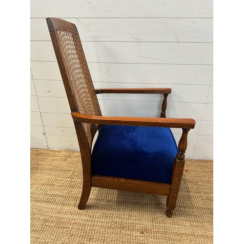 81 - An oak cane backed arts and crafts style arm chair upholstered in blue