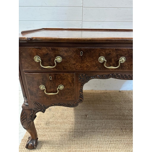 94 - a Georgian style walnut knee hole desk with brass drop handles and galleried top on claw and ball fe... 