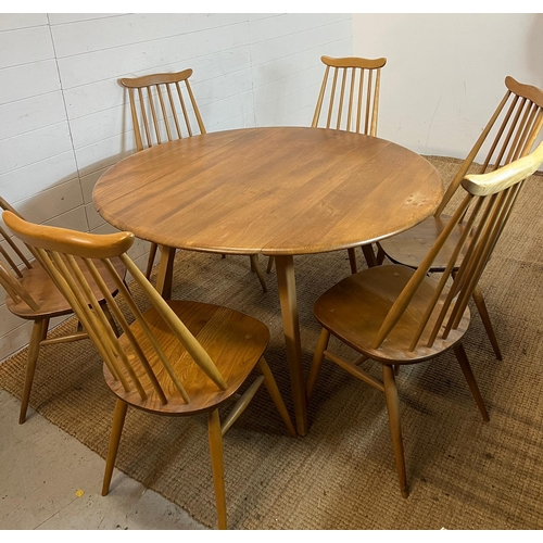 100 - A blondie Ercol circular drop leaf table with six stick back chairs (H72cm W124cm)