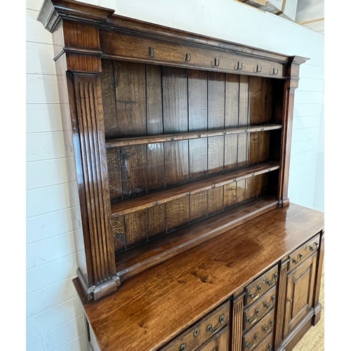 133 - An oak dresser with large plate rack sat on a cupboard base and drop handle (H208cm W177cm D55cm)