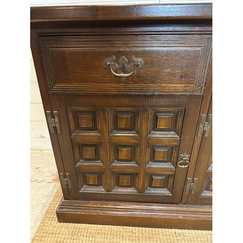 136 - An Arts and Crafts style sideboard, one long central drawer flanked by two shorter drawers and three... 