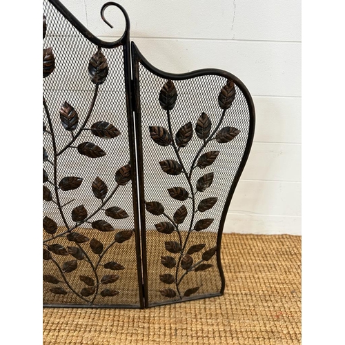 139 - A wrought iron and wire mesh fire guard with leaf details