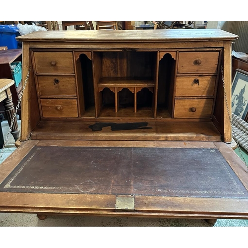 149 - A large pine bureau. The front fall opening to pigeon holes, drawers and a brown leather topped writ... 