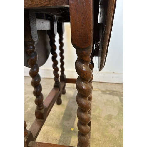 163 - An oak gate leg table on barley twist legs (H72cm W99cm D73cm)