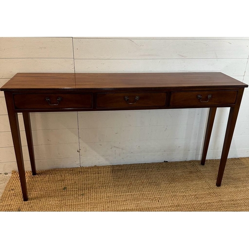 20 - A mahogany three drawer console table with brass drop handles (H77cm W138cm D32cm)