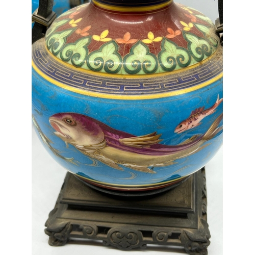 202 - A pair of china oil lamps with fish decoration to centre and metal handles depicting butterflies, st... 