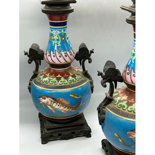 202 - A pair of china oil lamps with fish decoration to centre and metal handles depicting butterflies, st... 