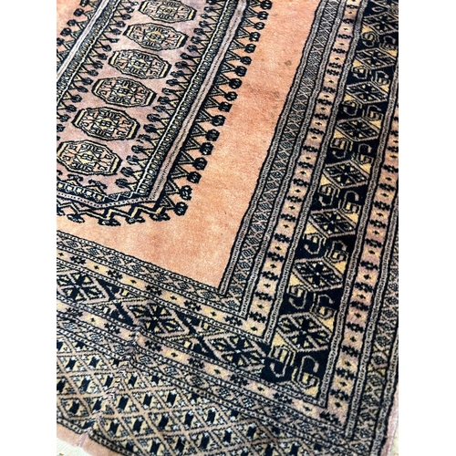 218 - A Pakistani style geometric rug with one central motif with pink grounds 105cm x 95cm